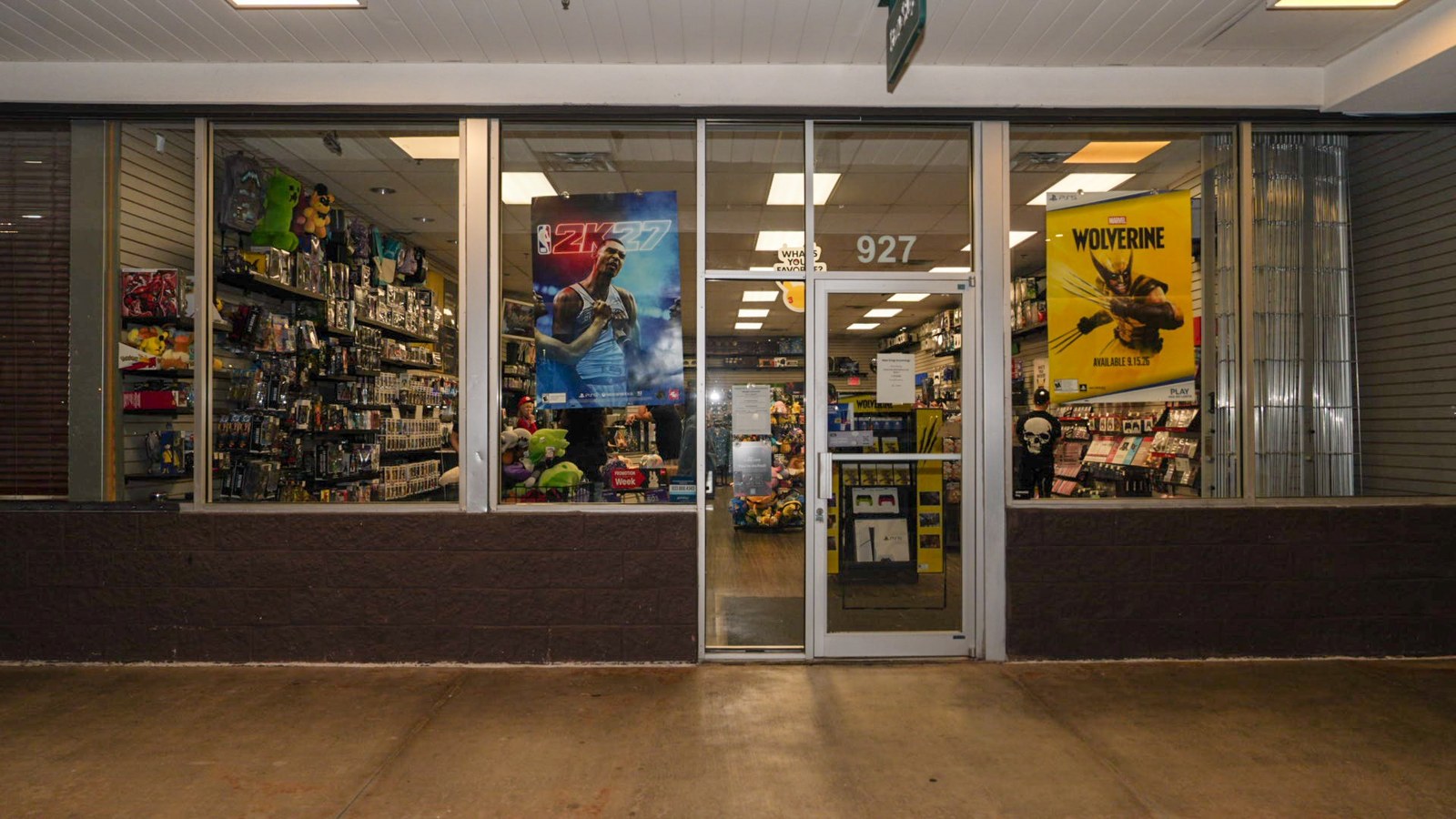 Storefront at night with glass doors, number 927 above the entrance and posters in the windows